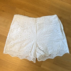 Vita broderade shorts med spetskant - Superfina vita shorts med broderade blommönster och hålbroderier. De har låg midja och en söt vågig spetskant längst ner. Så fina❣️