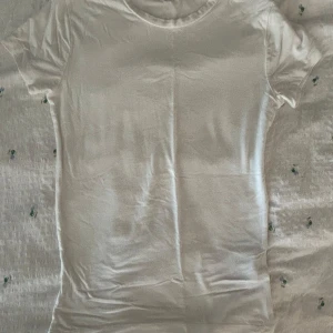 Vit basic t-shirt i bomull - Enkel och stilren vit t-shirt med rund hals och korta ärmar. Perfekt att matcha med jeans eller shorts för en clean look. Gjord i mjuk bomull som känns skön mot huden.