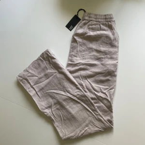 Beige linnebyxa - Beiga linnebyxor i storlek xs från Lager 157. Helt nya med lappen kvar. Byxorna har 1 bakficka och snörning vid midjan. Färgen syns bäst på bild 2. Köparen betalar frakten!