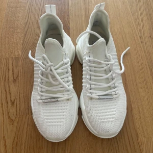 Vita chunky sneakers från Steve Madden - Snygga vita chunky sneakers från Steve Madden med stickad ovandel och tjock sula. Skorna har snörning och en modern, sportig look. Perfekta för dig som gillar streetstyle och vill ha bekväma skor med cool design.