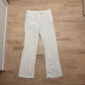 Vita raka kostymbyxor - Snygga vita kostymbyxor med raka ben och klassisk passform. Byxorna har hällor för bälte och stängs med dold knäppning. Perfekta för en clean och stilren look. Materialet känns mjukt och har en lätt struktur.
