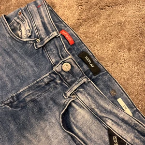 Replay jeans  - Säljer ett par Replay Hyperflex jeans i blå tvätt med slitningar och trasiga detaljer på benen.storlek: 27/30!!  Skick 8/10!! Nypris 1,8k Tar emot byten och skriv om fler bilder eller funderingar!