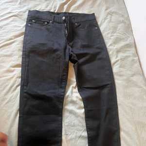 Svarta Levi's 511 jeans - Säljer ett par svarta Levi's 511 jeans med klassisk femficksdesign och snyggt läderpatch bak. Jeansen har en slim passform och raka ben, tillverkade i mjukt bomullstyg med lite stretch. Perfekta för dig som gillar stilrena och tidlösa jeans.