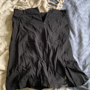 Svart kjol med slits från Vero Moda - Svart, stilren kjol från Vero Moda i storlek 36. Kjolen är knälång med en snygg slits framtill som ger en cool touch. Passformen är normal och materialet känns lätt och bekvämt. Perfekt att styla med en enkel topp eller hoodie.