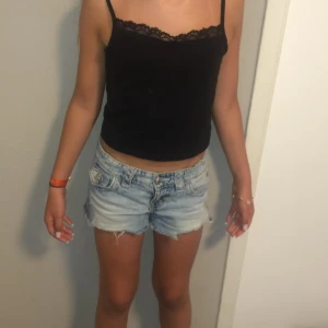 Svart linnetopp med spets från H&M - Svart croppad linnetopp från H&M med tunna axelband och snygg spetskant upptill. Perfekt till jeansshorts eller kjol för en chill sommarlook. Toppens material är mjukt och stretchigt för en bekväm passform.