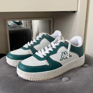Vita och gröna sneakers från Kappa - Snygga sneakers från Kappa i vitt och grönt med klassisk logga på sidan. Skorna är använda fåtal gånger och kommer vara rena vid leverans.