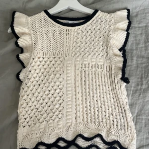 Vit stickad ärmlös topp från Zara - Superfin vit stickad topp från Zara med volangdetaljer på axlarna och svarta kontrastkanter. Använd fåtal gånger.