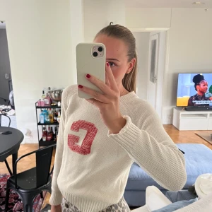 Vit stickad tröja med röd bokstav - Gant tröja. Tröjan har rund halsringning, ribbade muddar och är långärmad. Perfekt för dig som gillar en sportig och chill vibe.