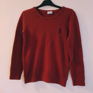 Röd stickad tröja från U.S. Polo Assn. Strl M - Säljer en röd stickad tröja från U.S. Polo Assn. i storlek M. Tröjan har ett grovt stickat mönster, rund halsringning och en liten broderad logga på bröstet. Perfekt för dig som gillar klassisk och enkel stil med en twist.  Helt skick dock ev lite ljusare i färgen
