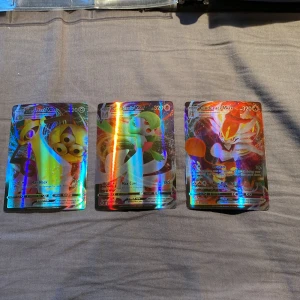 Pokémonkort VMAX - Aegislash, Gardevoir, Cinderace - Tre stycken holografiska Pokémon VMAX-kort: Aegislash VMAX, Gardevoir VMAX och Cinderace VMAX. Alla har 320 HP och färgglad, glansig yta. Perfekt för samlare eller Pokémon-fans som vill utöka sin kortsamling.