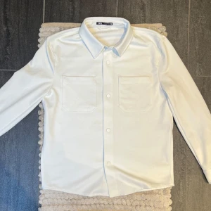 Zara Overshirt Vit - Fräsch vit overshirt från Zara, storlek M, i mycket fint skick. Enkel och mångsidig – passar lika bra till jeans som till chinos. Perfekt för vår/sommar.