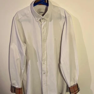 Vit Burberry skjorta  - Klassisk vit skjorta från Burberry med diskret broderad logga och skick 9/10. Finns qr kod och nypris är 5400 kr. Skjortan är i storlek S och passar någon mellan 180/170 och 65-55 kg😇😇😇