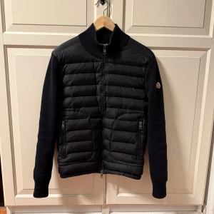 Moncler Cardigan - Säljer en snygg Moncler Cardigan i färgen svart med NFC Scan. Perfekt att ha nu inför sommarn. Skick: 8/10 använd ett fåtal gånger men fortfarande i fint skick. Storlek: S passar 165-178cm. Pris: 2500kr tar emot byten också. Pris kan diskuteras vid snabb affär💨 Kom DM vid funderingar eller fler bilder🥰