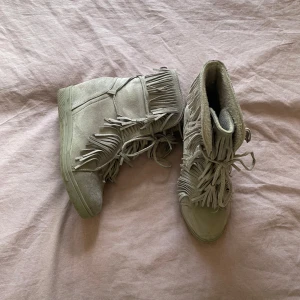 Grå mockaboots med fransar - Säljer dessa Isabel marant-liknande gråa mocka bootsen med fransar då jag har liknande. Skorna har snörning framtill och kilklack. Storlek 38 och är enkla att gå i & så fina nu på våren💞💞