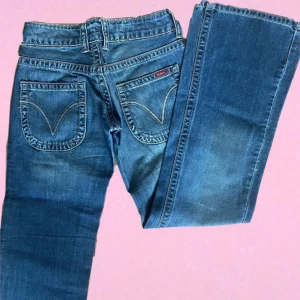 Blå bootcut/flared jeans från blend\replay - Säljer ett par klassiska blå bootcut jeans från Replay med snygga kontrastsömmar och bakfickor med dekorativa sömmar. Jeansen har normal passform och låg midja, perfekta till vardagsstilen.