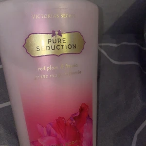 Pure Seduction Body Lotion från Victoria's Secret - En body lotion från Victoria's Secret i doften Pure Seduction med inslag av röd plommon och fresia. Flaskan är rosa med guldiga detaljer och har en dekorativ blomma på framsidan. Perfekt för dig som gillar fruktiga och blommiga dofter. Det är mer än hälften kvar. PRIS GÅR ATT DISKUTERA!!