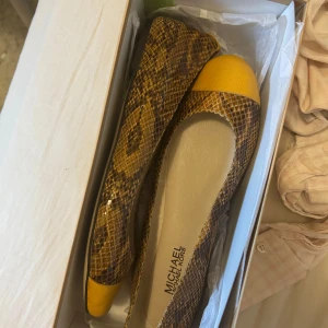 Gula ballerinaskor med ormmönster från Michael Kors - Säljer ett par ballerinaskor från Michael Kors med snyggt ormmönster i brunt och gult. Skorna är i strl 38/39 och nypris 1100 kr. Perfekta nu till sommaren 💕