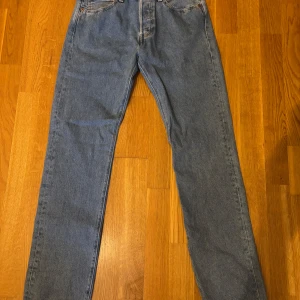Levi's 501 jeans blå - Klassiska blå Levi's 501 Slim jeans med raka ben och femficksmodell. Jeansen är tillverkade i 100% bomull och har en normal passform. Perfekta för dig som gillar tidlös denimstil.