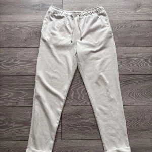 Vita mjukisbyxor från Zara - Säljer ett par vita mjukisbyxor från Zara med elastisk midja och dragsko. Byxorna har raka ben och två bakfickor. Perfekta för en avslappnad stil och riktigt sköna att ha på sig.