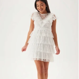 Lace Frill Short Dress - Superfin vit spetsklänning från Bubbleroom med flera lager volanger och v-ringad volangkrage. Klänningen har korta ärmar i spets och passar perfekt till student, konfirmation eller skolavslutning! Nypris är 899 kr och den är endast använd en gång.💞Storlek M men passar mig bra och har S i vanliga fall!