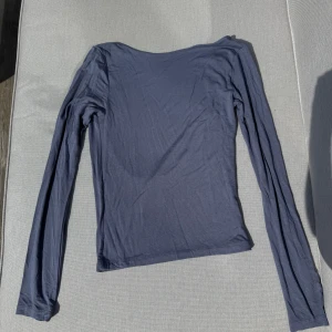 Mörkgrå långärmad topp från Ginatricot - Säljer en mörkgrå/blå långärmad topp från Ginatricot. Toppen har en djup, öppen rygg och är tillverkad i ett mjukt, stretchigt material. Storlek M