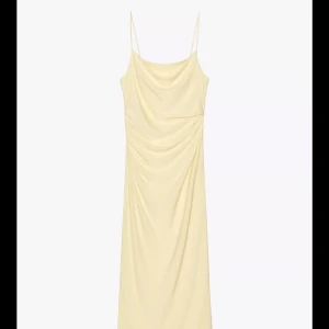 Ljusgul långklänning med tunna axelband - Säljer en elegant ljusgul långklänning med tunna axelband och draperad front. Klänningen har en mjuk, flytande passform och är perfekt för somriga tillfällen. Enkel och stilren design som ger en sofistikerad look. Helt ny med prislapp!! Från Zara 