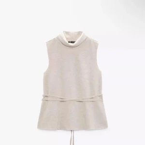 Beige ärmlös polotopp från Zara - Snygg beige ärmlös polotopp från Zara! Toppen har en hög krage och ett knytband i midjan för en justerbar passform. Fint skick! 💗