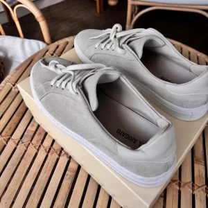 Ljusbeige sneakers från Axel Arigato - Snygga beige sneakers från Axel Arigato i mocka med vita detaljer och platt vit sula. Sparsamt använda. Priset kan diskuteras vid snabb affär!Nypris 2650kr 