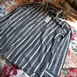 Svartvit randig skjorta  - Säljer en svartvit randig skjorta från Only & Sons. Skjortan har långa ärmar, klassisk krage och knäppning framtill. Perfekt för dig som gillar en avslappnad men ändå stilren look.