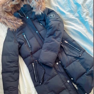 Svart dunjacka från Rockandblue - Säljer en svart längre jacka från Rockandblue med päls. Perfekt för kalla dagar 🤍 Använd endast två vintrar och är fortfarande i bra skick! Köpt för 4499kr, säljes för 1700 kr men pris kan diskuteras! 