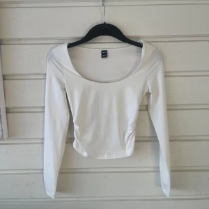 Vit långärmad topp från SHEIN - Säljer en vit långärmad topp från SHEIN i storlek Petite XXS. Toppen har en rundad, djup urringning och rynkade detaljer i sidorna. Tillverkad i mjuk och stretchig polyesterblandning. Perfekt för en stilren och enkel look. Skriv om du har frågor!💕💕