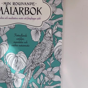 Min Rogivande Målarbok - En målarbok med förtrollande världar, mandalas och vackra naturmotiv. Omslaget är turkost med svartvita illustrationer av papegojor och blommor. Inuti finns detaljerade och meditativa motiv att färglägga själv. Och massa annat skit 