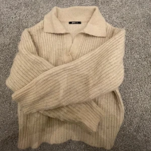 Beige stickad tröja med krage från Gina Tricot - Säljer en beige stickad tröja från Gina Tricot i storlek XS. Tröjan har en klassisk krage och långa ärmar, samt ribbad struktur som ger en mysig känsla. Perfekt för kyligare dagar och enkel att matcha med olika outfits.