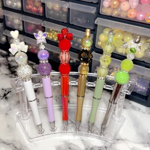 Dekorativa fancy pennor  med pärlor och figurer - Säljer unika fancy pennor dekorerade med färgglada pärlor, glitter och söta figurer som hjärtan, fjärilar, djur och blommor. Pennorna finns i flera färger som lila, röd, grön, guld, rosa och svart. Perfekt för att piffa upp skrivbordet eller som present.