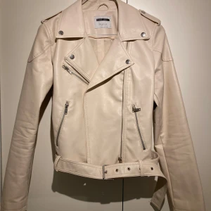 Beige skinnjacka från Noisy May - Snygg beige jacka från Noisy May i kort modell. Läderimitation. Skärp i midja, fin både stängd och öppen över klänning eller till jeans. Som ”kavaj” inomhus eller jacka till vår och sommar. Köpt på Vero Moda för ca 800kr för ett par år sedan men använd endast ett par tillfällen. 