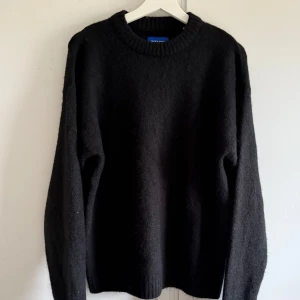 Svart stickad tröja från Jack & Jones - En klassisk svart stickad tröja från Jack & Jones. Tröjan har rund halsringning och långa ärmar med ribbade muddar vid hals, ärmslut och nederkant. Perfekt för lager-på-lager under kyliga dagar.