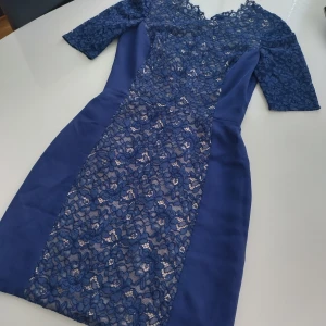 Blå spetsklänning från Barneys New York - Elegant blå klänning från Barneys New York med vackra spetsdetaljer och halvärmade ärmar. Klänningen har figurnära passform och är fodrad med silke för en lyxig känsla. Perfekt för speciella tillfällen.