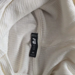 Vit croppad hoodie från Sisters  - Säljer en vit croppad hoodie från Sisters . Tröjan har långa ärmar, ribbade muddar och huva. Perfekt för en avslappnad och trendig stil. Materialet är mjukt och ribbat för extra komfort.