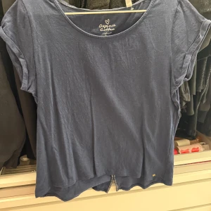 Blå t-shirt i bomull från Organic Cotton - En enkel blå t-shirt i mjuk bomull från Organic Cotton. Modellen har rund halsringning och korta ärmar. Perfekt för en avslappnad stil.