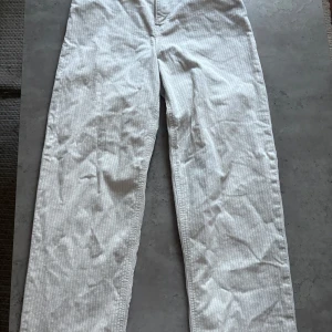 Vita manchesterbyxor från Lee - Säljer ett par vita manchesterbyxor från Lee med diskret randigt mönster. Byxorna har klassisk femficksdesign och raka ben.Liten fläck förekommer men utöver det sparsamt använda