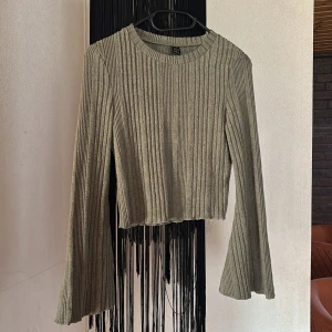 Grå ribbad croppad tröja från SHEIN - Säljer en grå ribbad croppad tröja från SHEIN. Tröjan har långa ärmar och en rund halsringning. Perfekt för att skapa en trendig och avslappnad look.