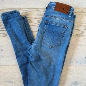 Blå jeans från tiger of sweden modell slight - Säljer ett par klassiska blå jeans från tiger of sweden. Jeansen har en smal passform och är perfekta till vardags. Snygga slitningar och normal midja. Storleken är 30/32. Säljer för att jag behöver pengar till nya skor.