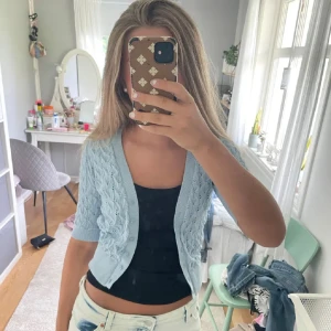 Ljusblå kofta från Kappahl - Säljer en ljusblå kofta från Kappahl i storlek S. Koftan har ett fint stickat mönster, knappar framtill och trekvartsärmar. Perfekt att slänga över en topp för en söt och fräsch look.