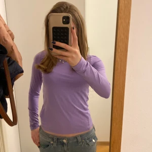 Ljuslila långärmad träningströja från SOC - Säljer en ljuslila långärmad träningströja från SOC. Tröjan har rund halsringning och är tillverkad i ett syntetmaterial med ventilerande panel på ryggen för extra komfort under träning. Perfekt för dig som vill ha en snygg och funktionell topp!