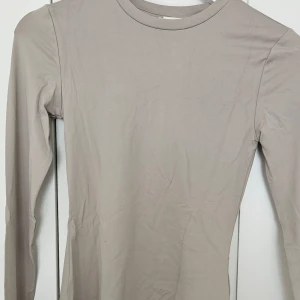 Beige långärmad topp - Säljer en enkel och stilren beige långärmad topp med rund halsringning. Perfekt att styla till olika outfits och funkar året runt. Mjuk och stretchig känsla i materialet.