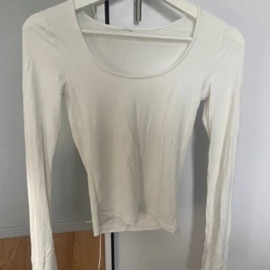 Vit långärmad topp - En enkel och stilren vit långärmad topp med rund halsringning. Perfekt att matcha med jeans eller kjol för en clean look. Tunn och mjuk i materialet, passar året runt.