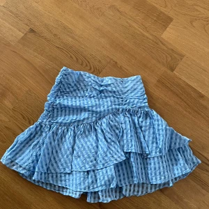 Asymmetrisk volangkjol från H&M - Kort kjol i blått och vitt med rutigt mönster och volanger. 