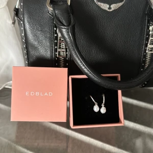 Edblad örhänget  - Ett par silvriga örhängen från Edblad, aldrig använda. Köpte dom för 399kr och mitt pris är 250kr. Skicket är 10/10 eftersom dom aldrig är använda. Skriv för mer frågor!!