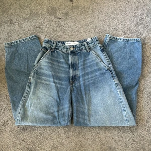 Blåa baggy bershka jeans - Supersköna baggy jeans från bershka med snygga fickor. Använda endast två gånger. Dom är väldigt baggy och har en ganska hög midja. Skriv privat ifall du har några frågor. Midjemåttet är 33 rakt över💞