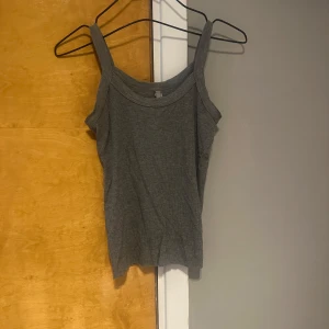 Grå ribbad linnetopp - Säljer en Skims grå ribbad linnetopp med breda axelband. Perfekt att matcha med jeans eller kjol för en avslappnad look. Mjuk och stretchig i materialet.